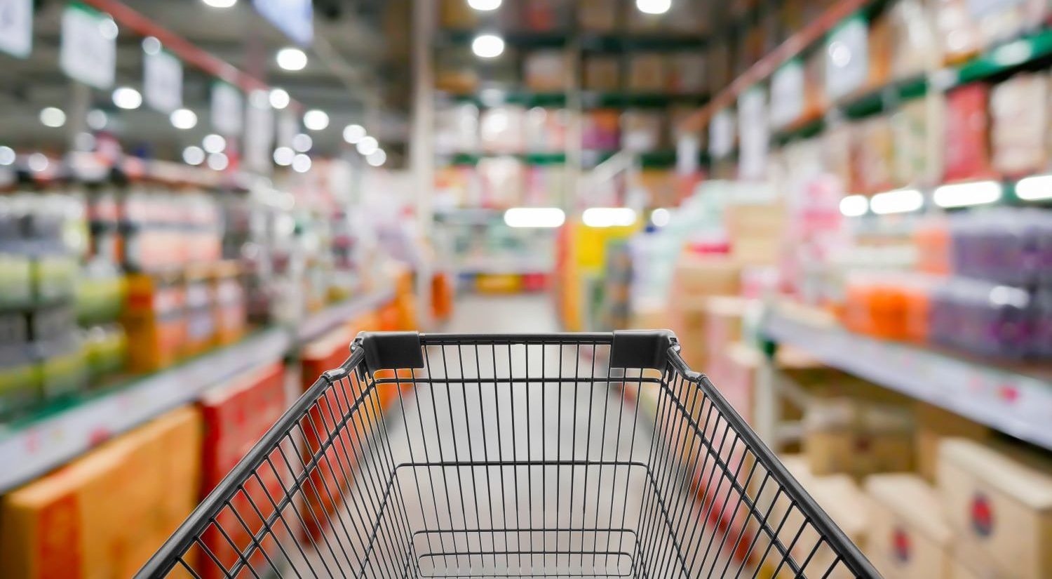 In focus shopping cart with out of focus grocery aisles in the background.