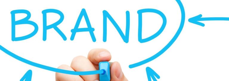Hand holding a bright blue highlighting writing the word "Brand" on a white board in blue illustrating the importance of quantitative brand research.