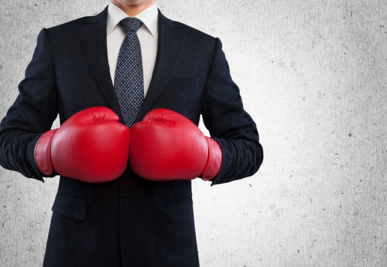 Businessman from neck down wearing boxing gloves.